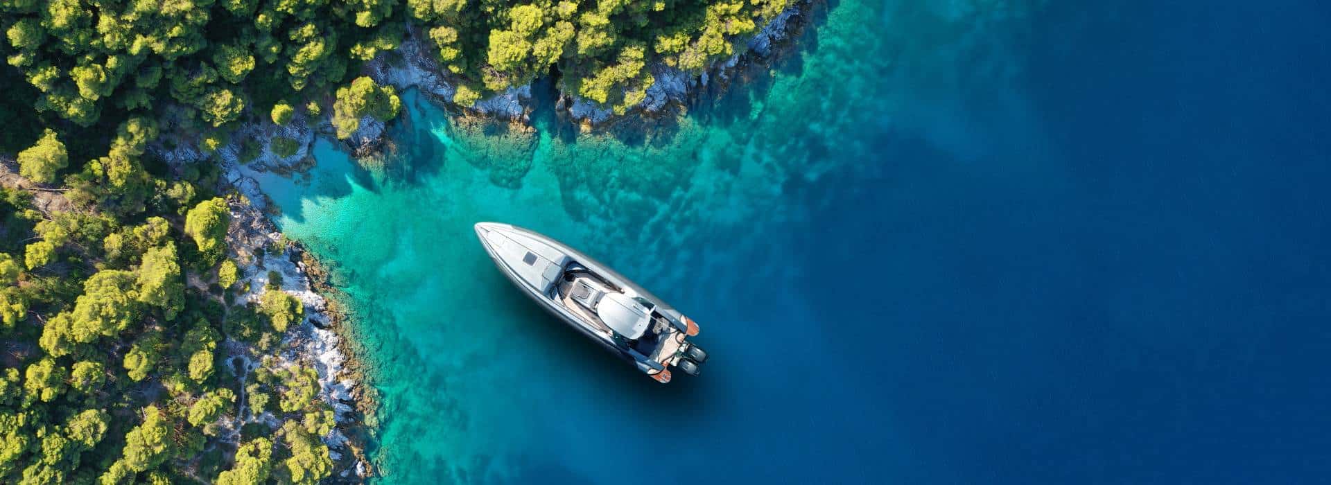 Luxury boat on turquoise water with lush green islands in the background.